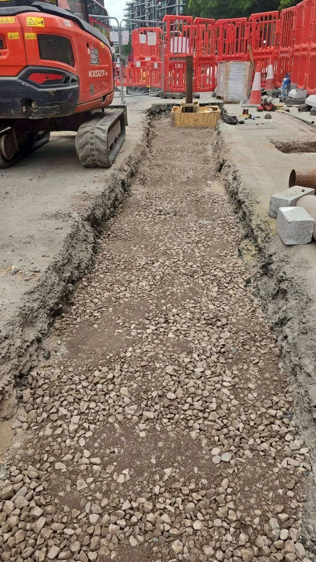 A trench dug out and filled with crushed stone as the sub-base, before the slabs are laid